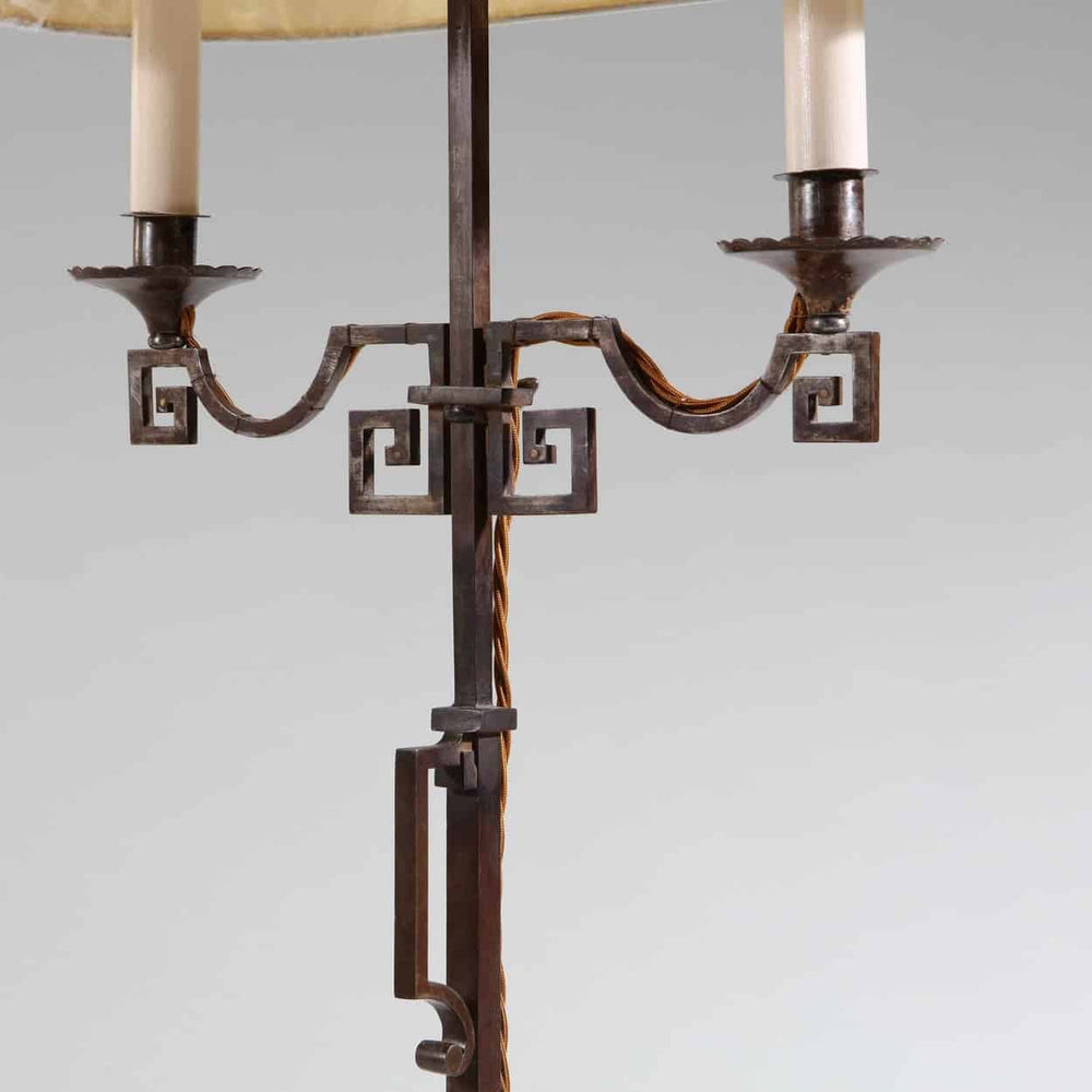 A patinated Steel floor standing bouillotte lamp with adjustable two branch shaded light and decorative key scroll details.
