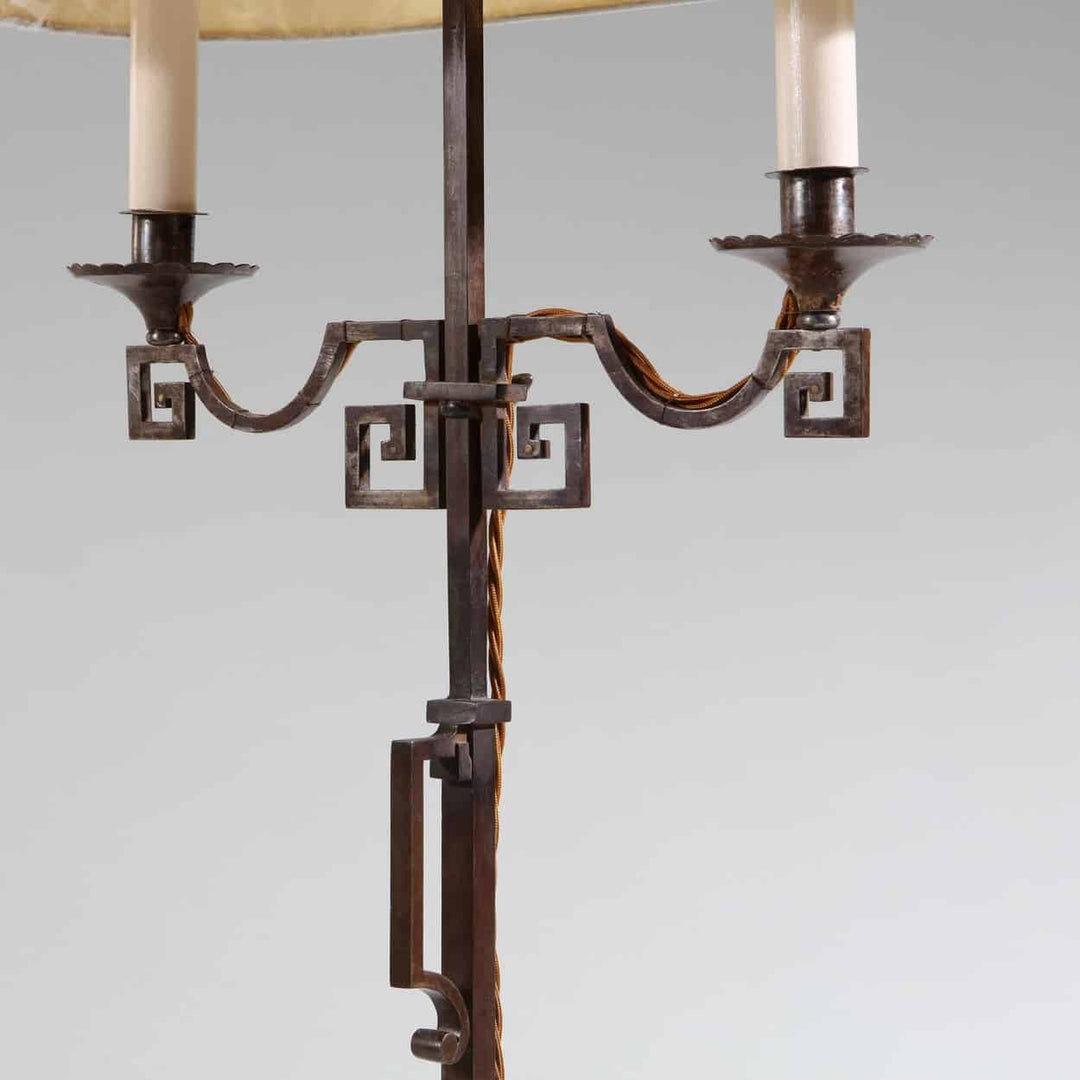 A patinated Steel floor standing bouillotte lamp with adjustable two branch shaded light and decorative key scroll details.