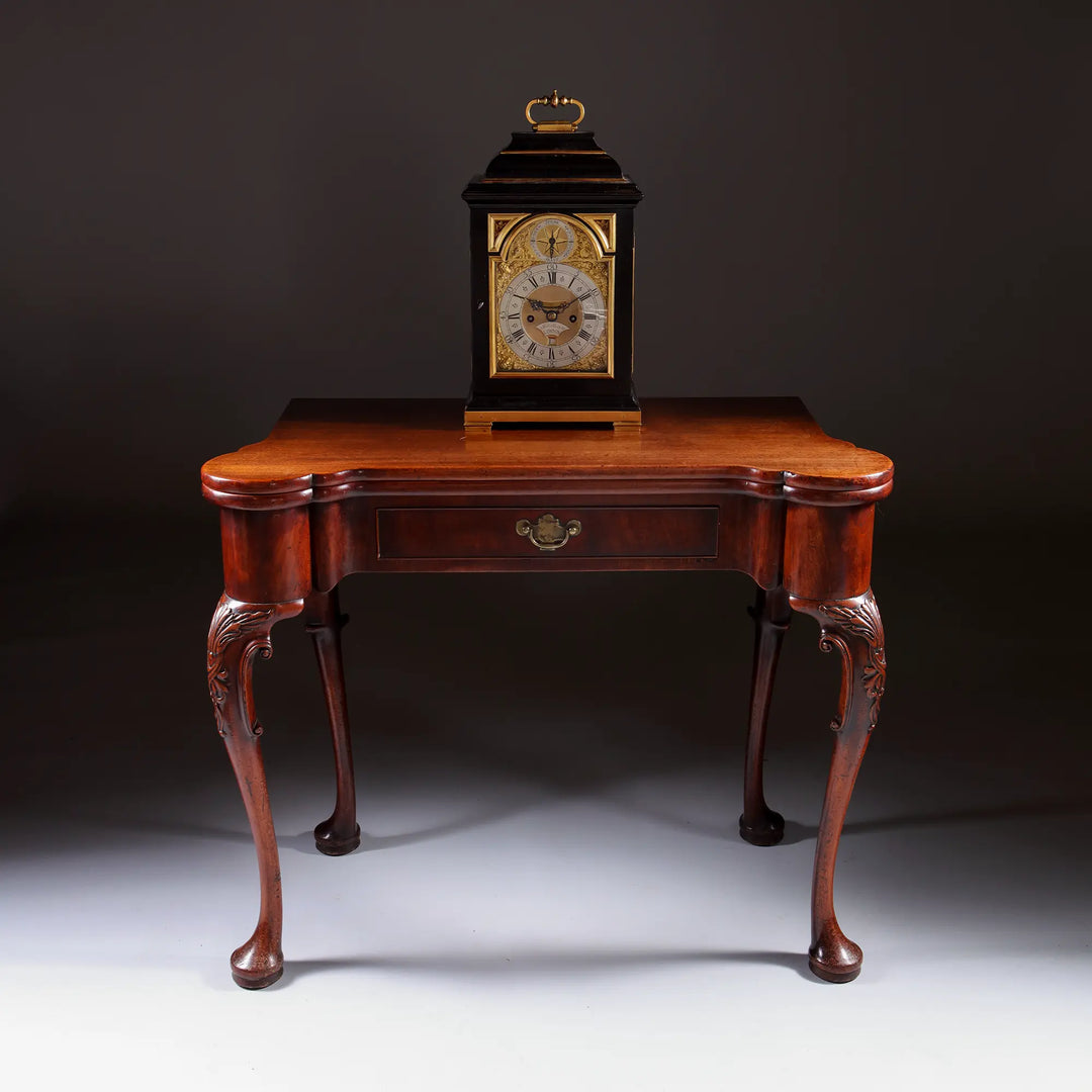 Mid 18th century ebony and gilt bronze bracket clock by John Ellicott displayed on antique wooden table Nwtiques