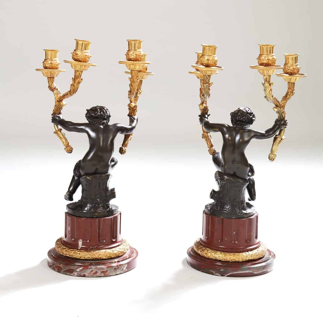 Pair of gilt bronze candelabra with seated bronze putti on rouge marble bases by Nwtiques