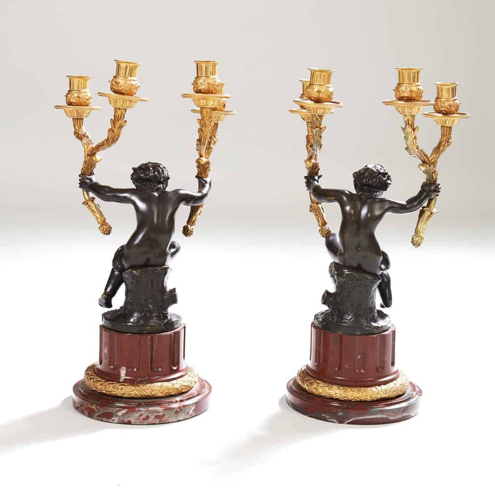 Pair of gilt bronze candelabra with seated bronze putti on rouge marble bases by Nwtiques