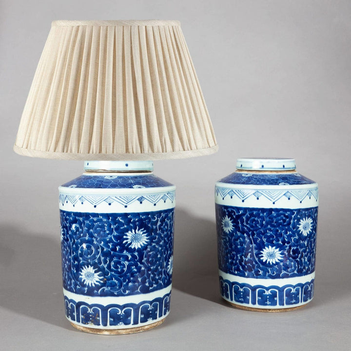 Pair of Chinese Blue and White Porcelain Ginger Jars as Lamps with floral designs and beige lampshade.