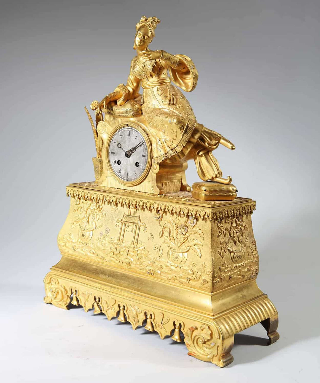 A 19th-century gilt bronze Ottoman mantle clock by Nwtiques featuring a seated lady and intricate details.