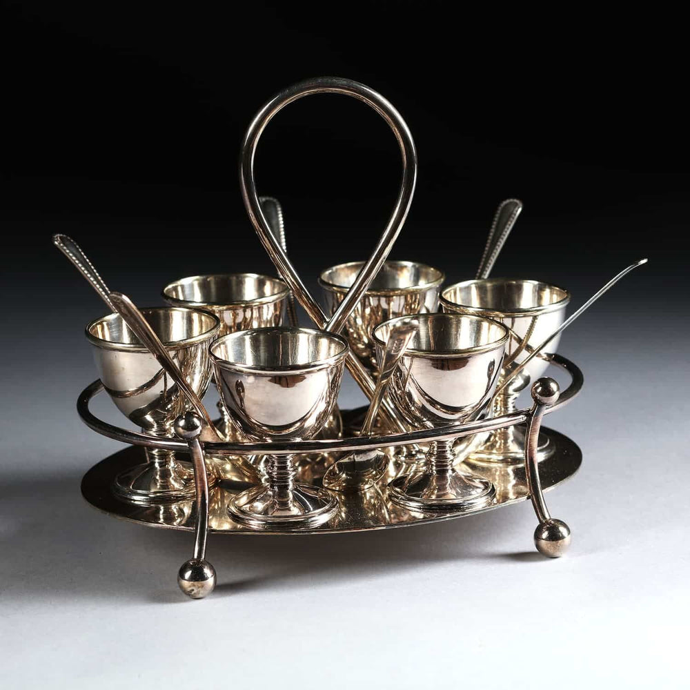 Hukin & Heath silver plate six egg cruet with spoons on ball feet by Nwtiques