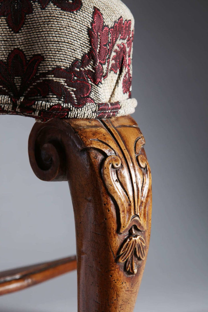Close-up of ornate carved walnut leg and floral upholstery on an 18th century Italian stool by Collection CK20.