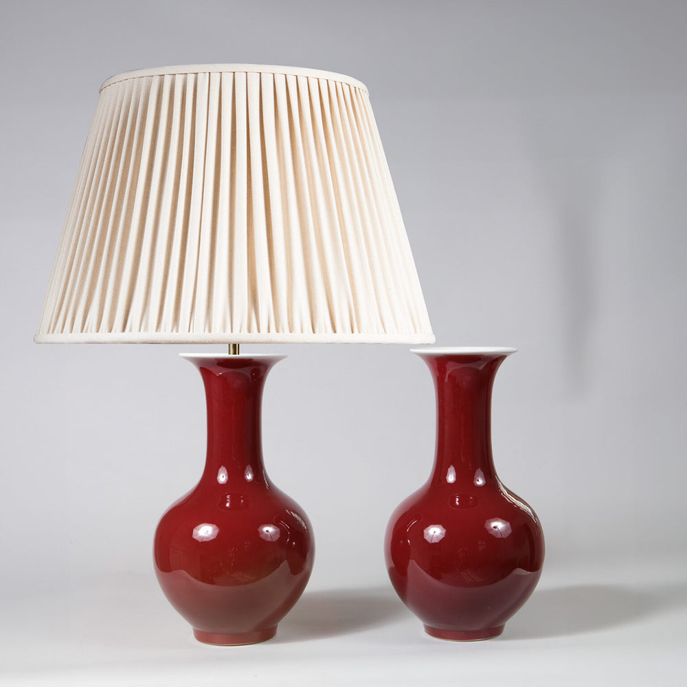 Pair of Sang de Boeuf Bottle Vases as Table Lamps with red glaze and cream pleated shade on one lamp.