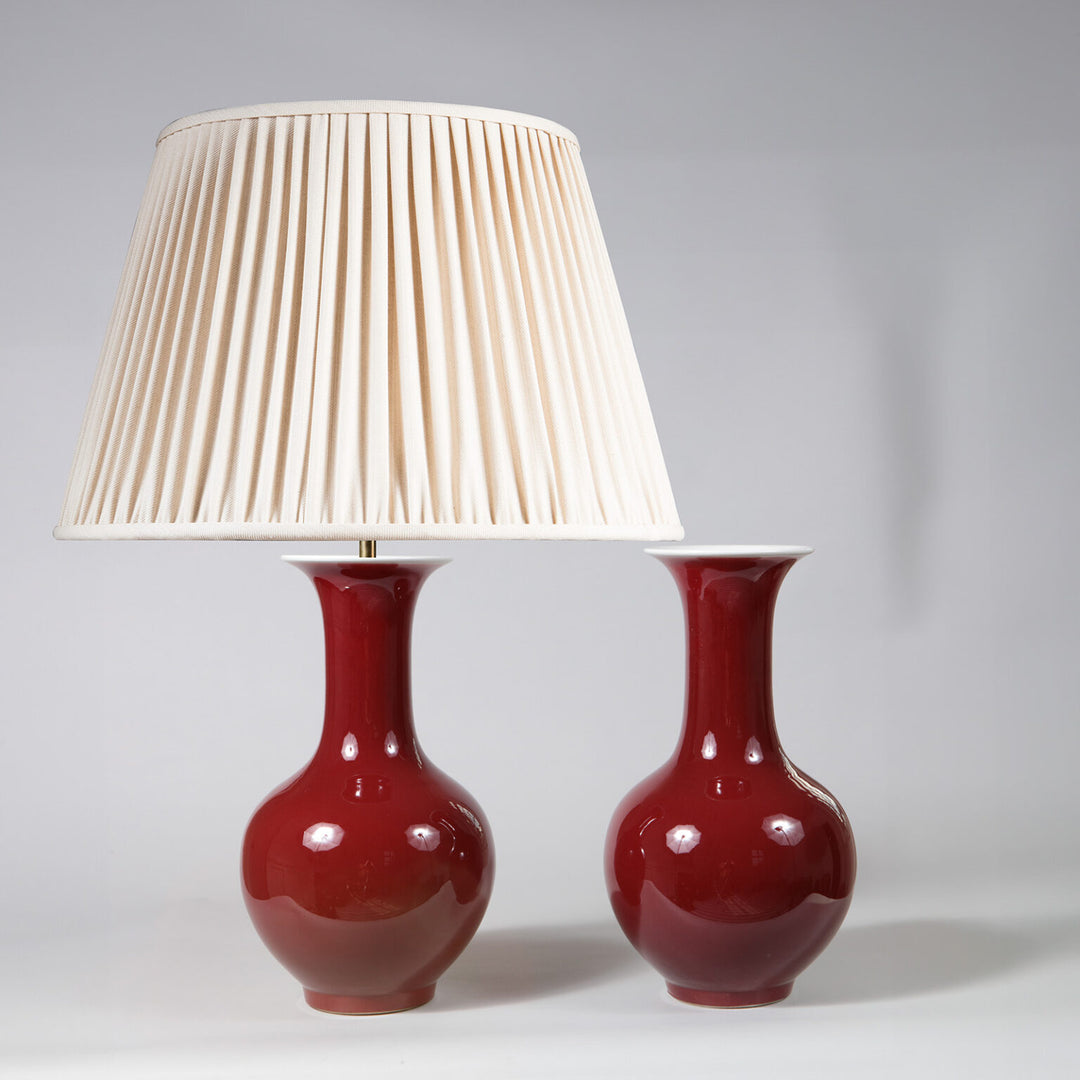 Pair of Sang de Boeuf Bottle Vases as Table Lamps with red glaze and cream pleated shade on one lamp.
