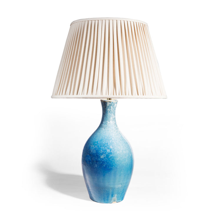 Blue crystalline glaze ceramic table lamp by Nwtiques with a soft pleated cream fabric shade