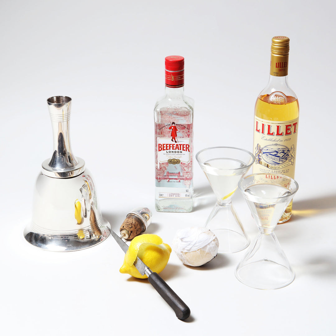 Asprey Bell Shaped Cocktail Shaker by Collection TH10 with gin, Lillet, peel, and martini glasses on white background