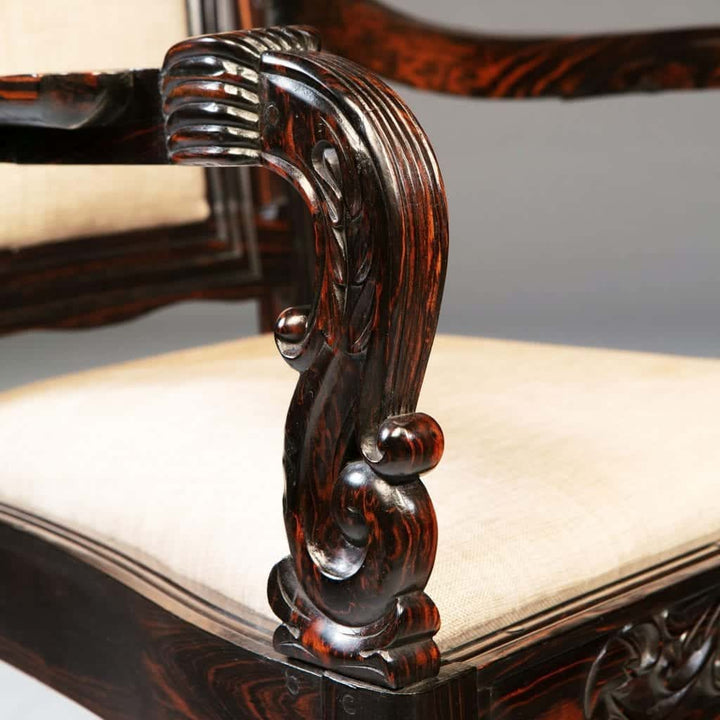 Close-up of finely carved calamander wood armchair armrest with cream upholstered seat by Nwtiques
