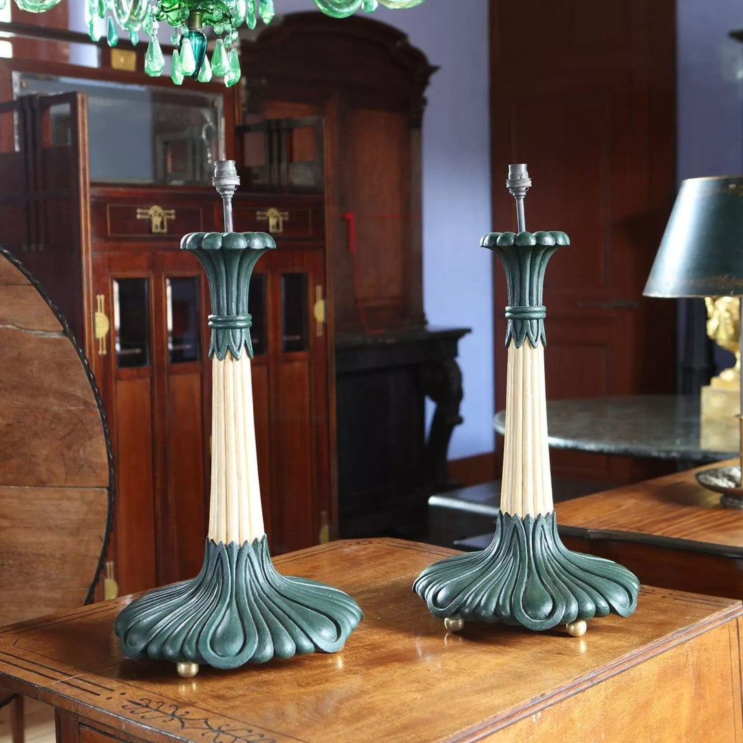 Pair of Foliate Column Lamps with cream lacquered columns, dark green bases, and brass ball feet on wooden table.