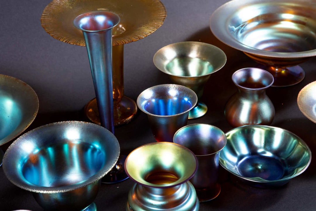 23 iridescent Art Deco WMF Myra glass bowls and vases in varied shapes from Collection TH20 displayed on a dark surface
