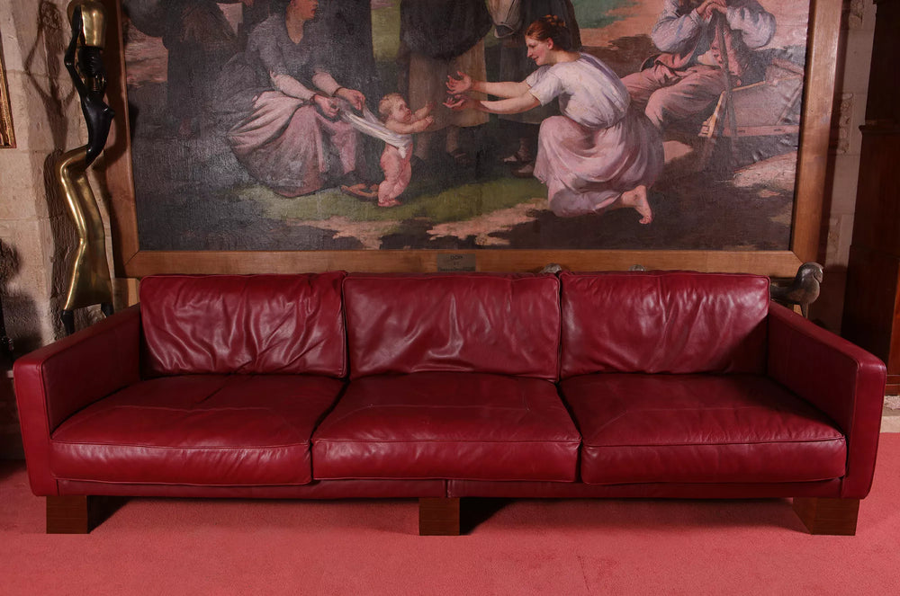 Elegant 20th-century red leather sofa by Collection NE10 with mahogany block feet and seating for three.