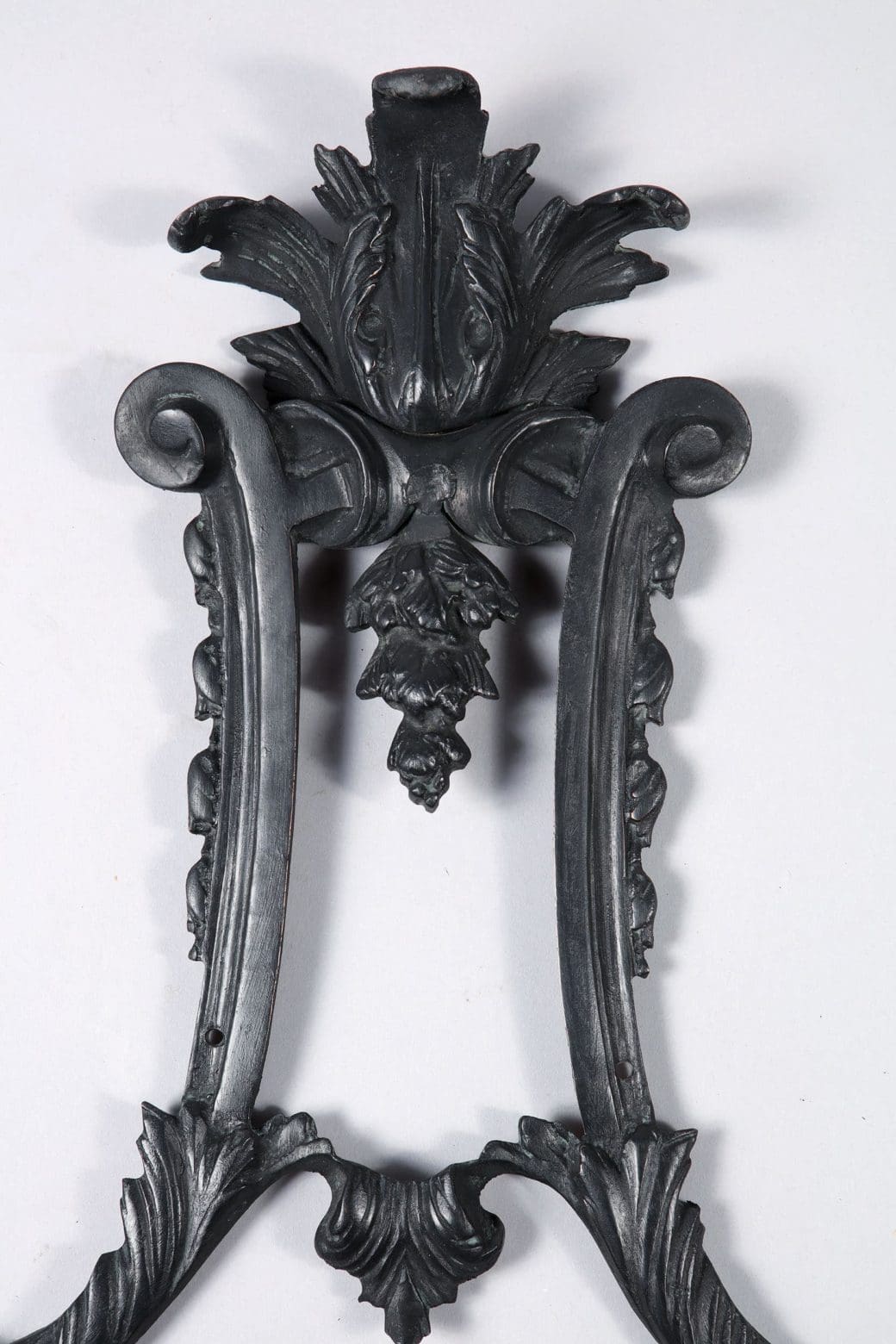 Close-up of ornate dark bronze Louis XIV style wall applique by Collection TH10 with detailed leaf and scroll designs