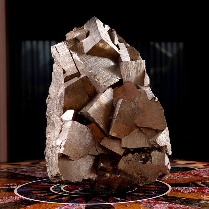 Pyrite specimen from Collection CK10 with metallic cubic crystals, displayed on a decorative surface against dark background
