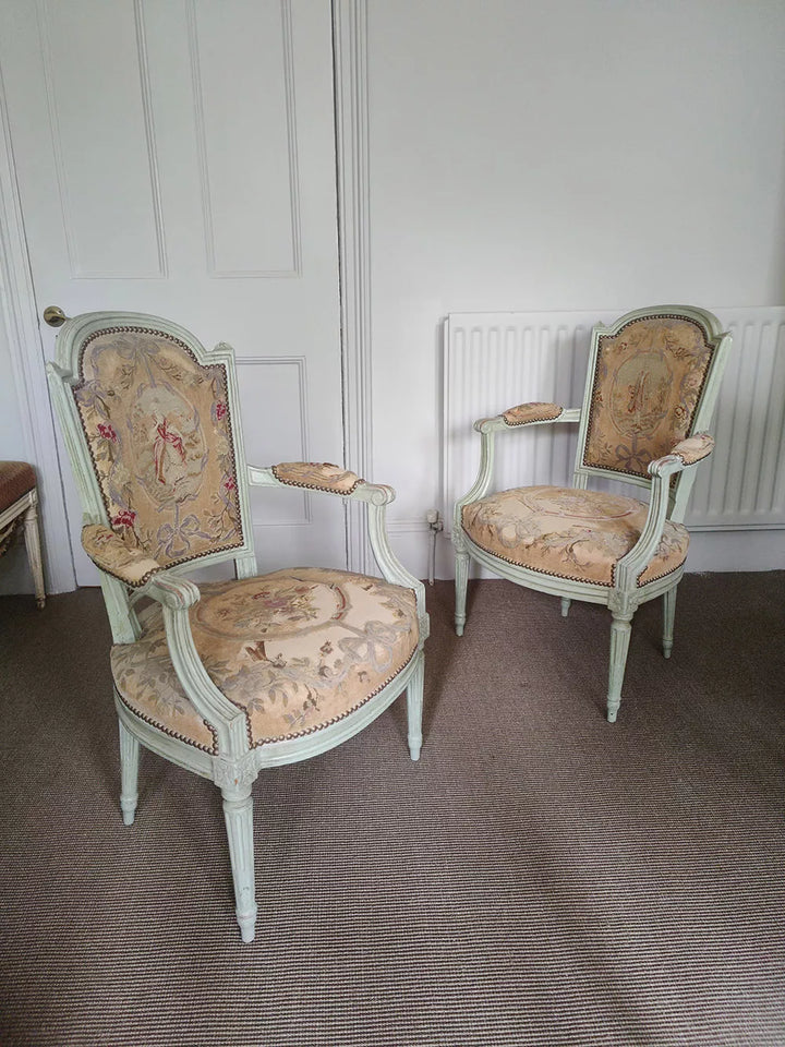 Two Louis XVI painted fauteuils with needlework upholstery by Nwtiques in a classic room setting