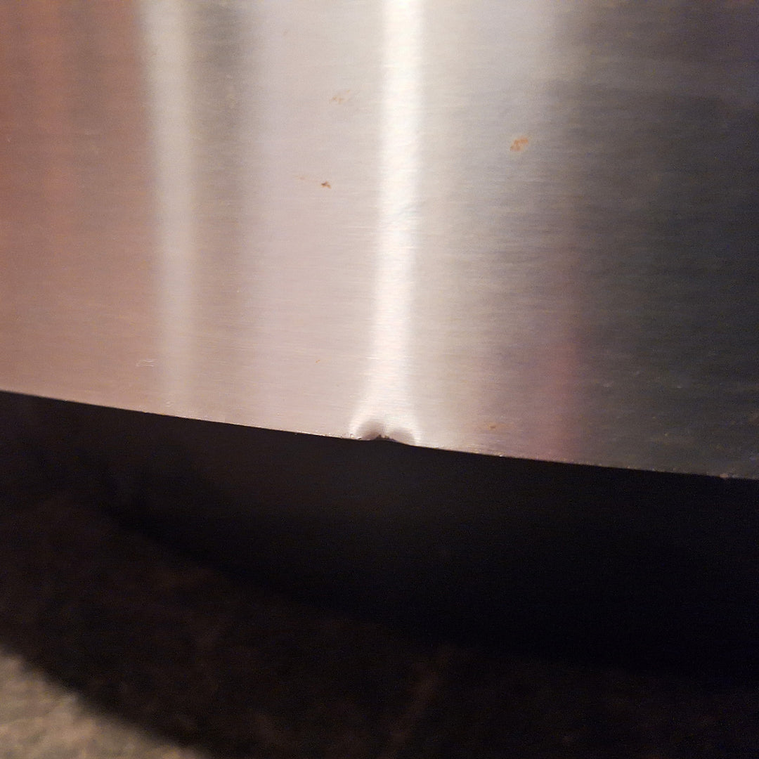 Close-up detail of brushed steel edge with small dent from TRG coffee table by Nwtiques