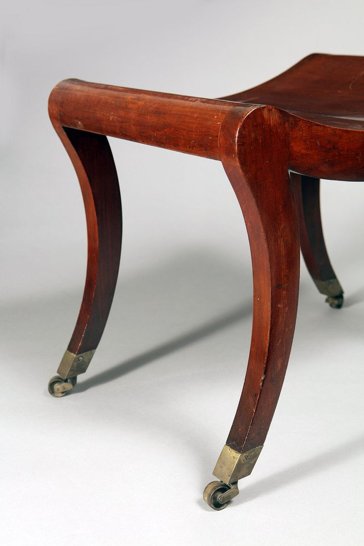 Close-up of Regency mahogany sabre leg with brass caster wheel from Collection TH10 saddle stool