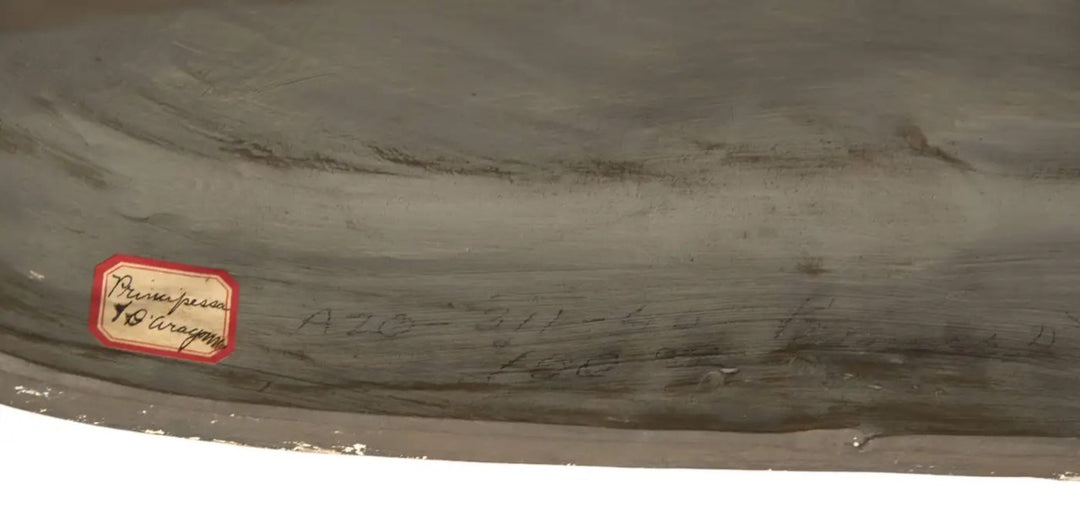 Close-up of the base of a terracotta portrait bust by Nwtiques, showing a handwritten label and inscriptions.