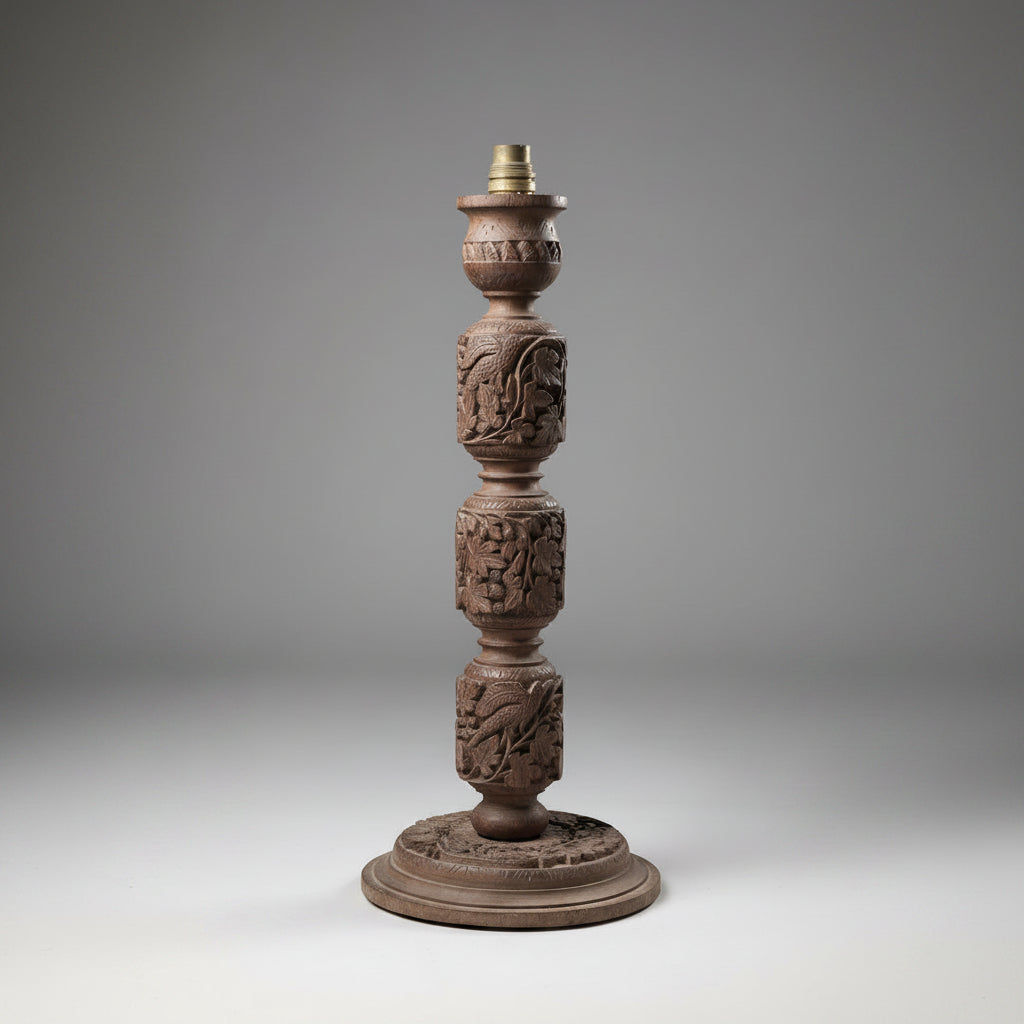 Decorative wooden lamp base with intricate carvings on a gray background