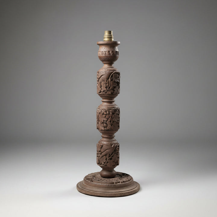 Decorative wooden lamp base with intricate carvings on a gray background