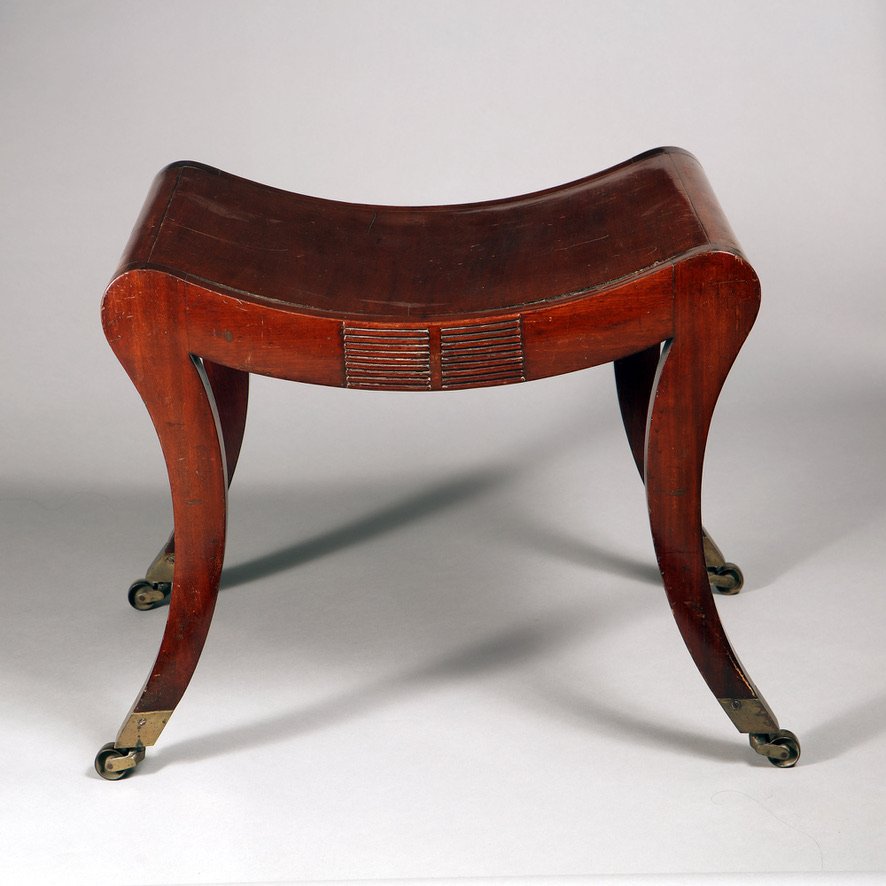 Regency mahogany sabre legged saddle stool with brass casters from Collection TH10 showcasing elegant craftsmanship