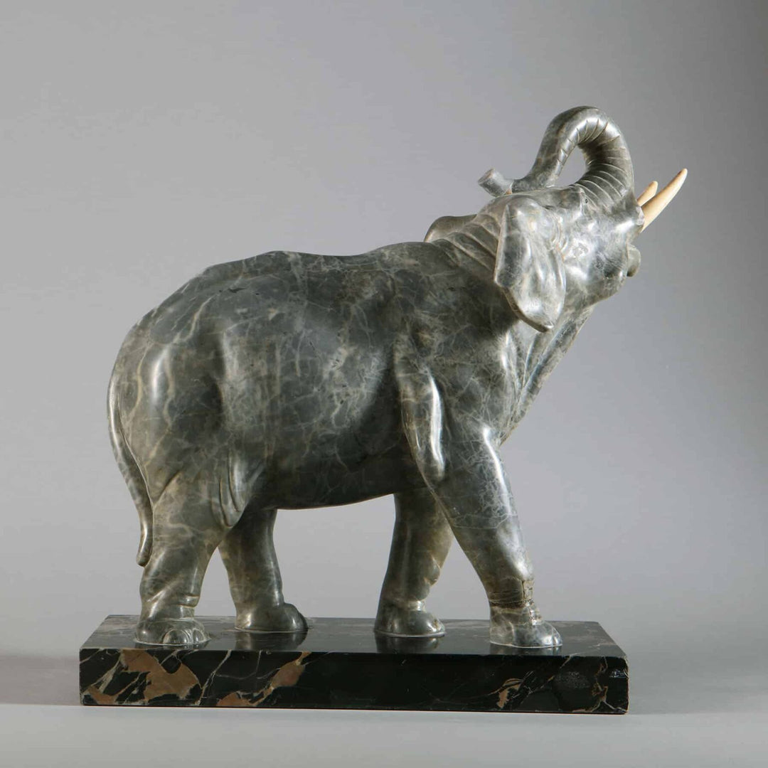 Grey Marble sculpture of an Elephant with trunk raised, carved from grey marble, mounted on a Portoro marble base.