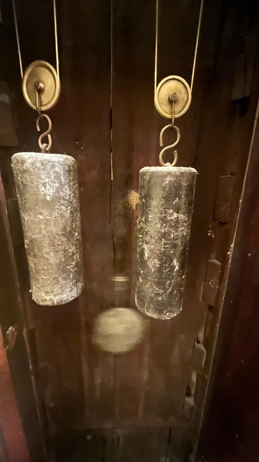 Close-up of two aged clock weights and pendulum inside an antique wooden longcase clock by Collection PK10