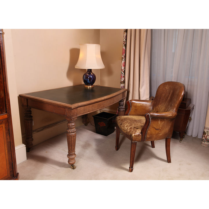 19th century late Georgian style leather desk chair with time-worn patina by Collection TH30 next to antique wooden desk and lamp
