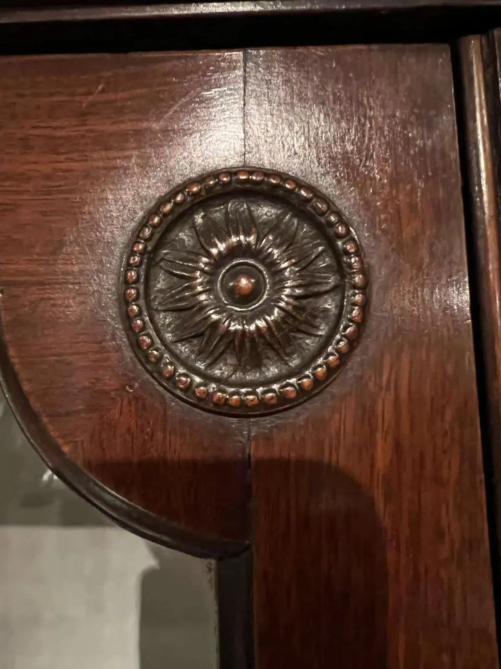 Close-up of decorative carved paterae detail on mahogany wood from Nwtiques George III bookcase