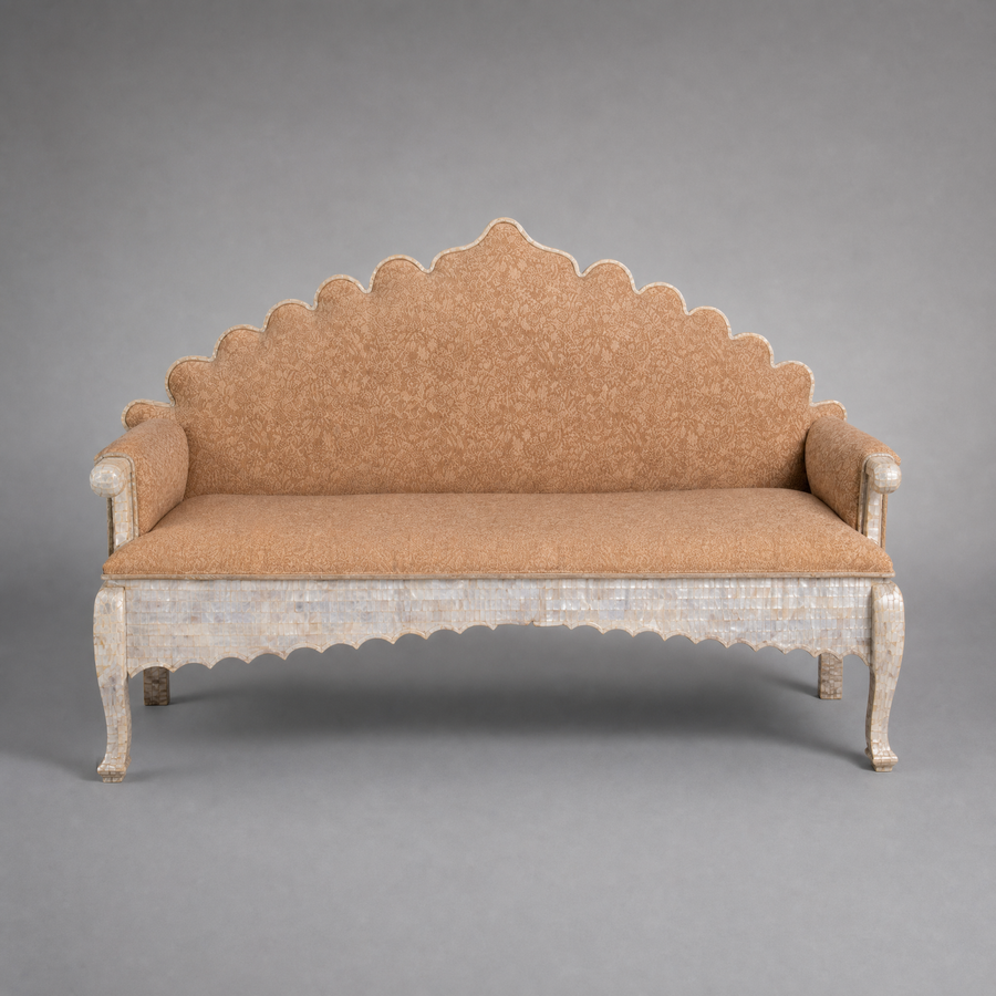 Decorative mother of pearl veneered sofa with scalloped backrest on a gray background