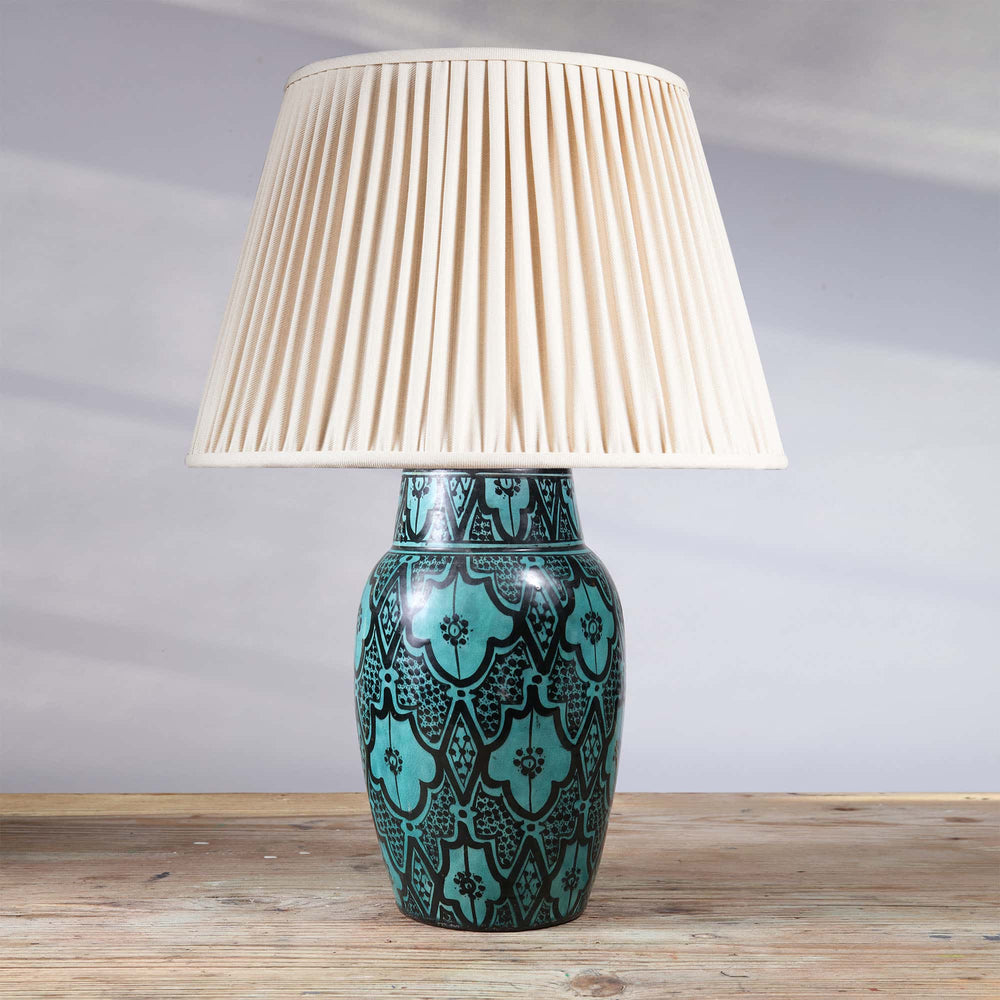 North African Turquoise Vase as a Table lamp with intricate Moroccan patterns and a pleated cream lampshade on wooden surface