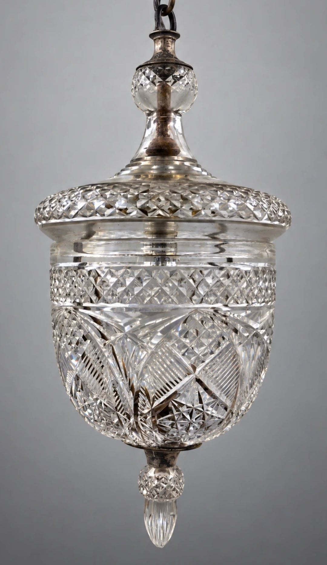A vintage cut glass pendant light fixture with a silver-toned metal top and chain, set against a neutral gray background. By Osler