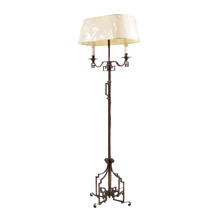 A patinated Steel floor standing bouillotte lamp with key scroll base and adjustable two-branch shaded light, circa 1920.
