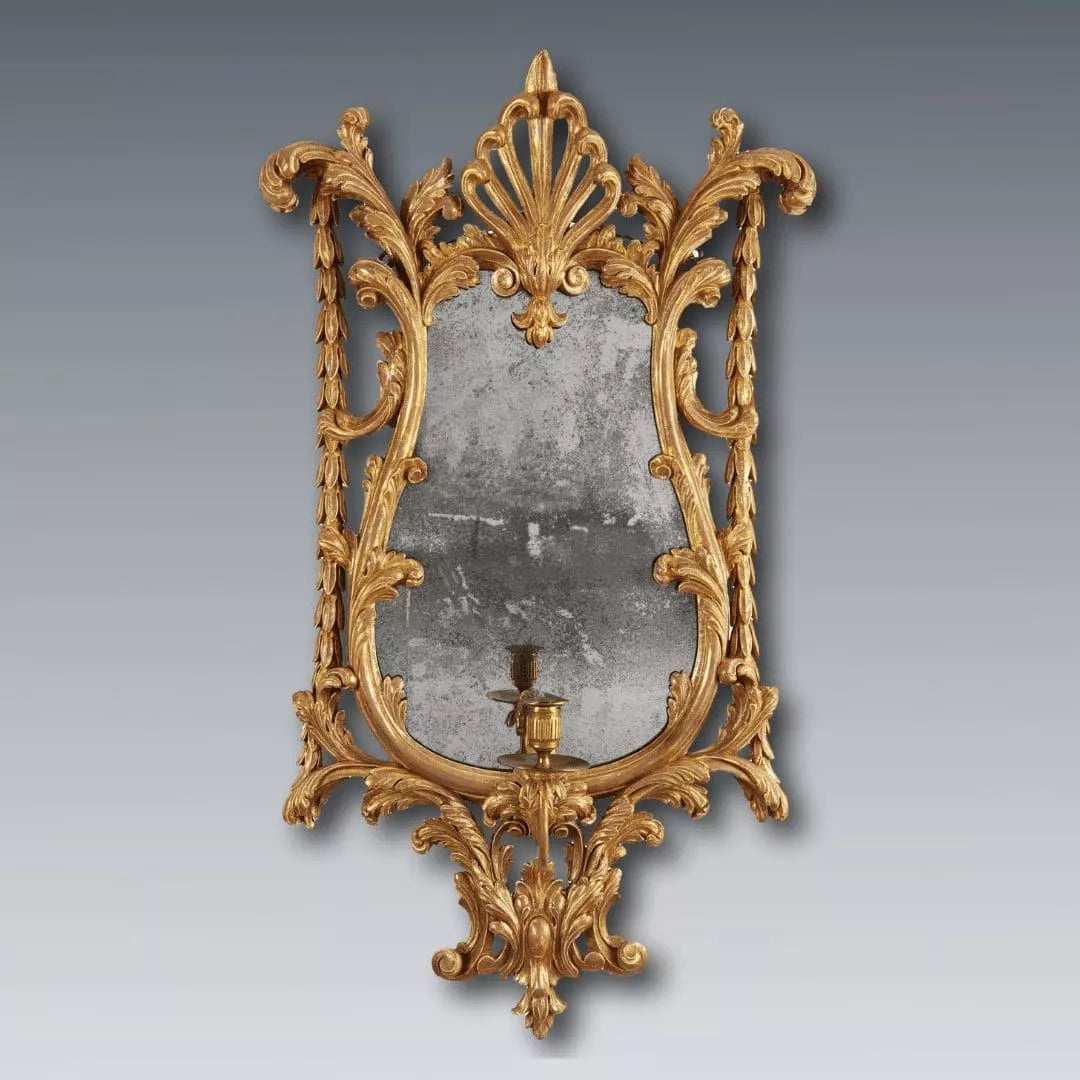 Georgian giltwood girandole mirror with carved anthemion, acanthus leaves, and single candle arm, circa 1780 England.