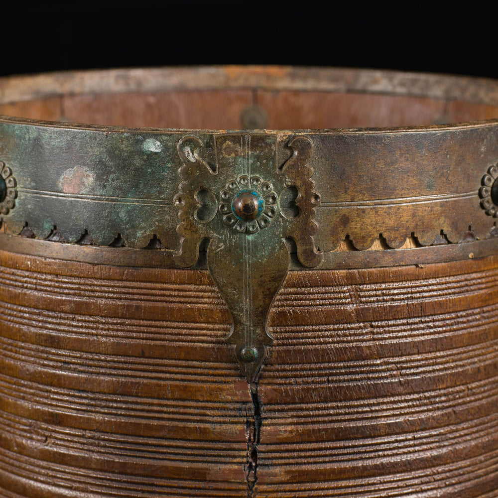 Close-up of 19th century brass bound teak rice measure from Collection EE20 with intricate ribbed design and detailed mounts