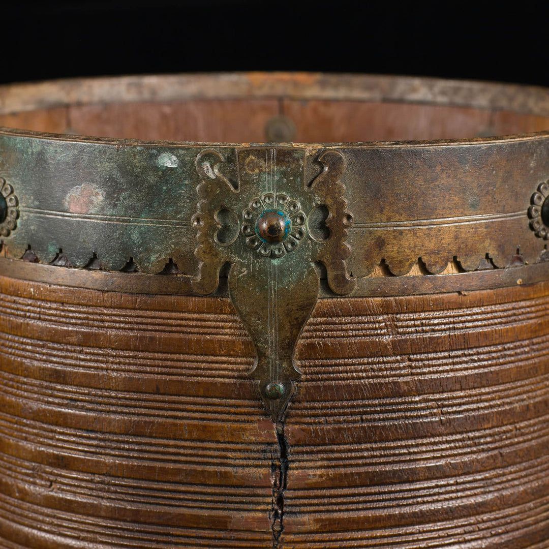 Close-up of 19th century brass bound teak rice measure from Collection EE20 with intricate ribbed design and detailed mounts